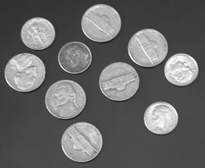 Photo of 10 silver coins on a dark grey background.